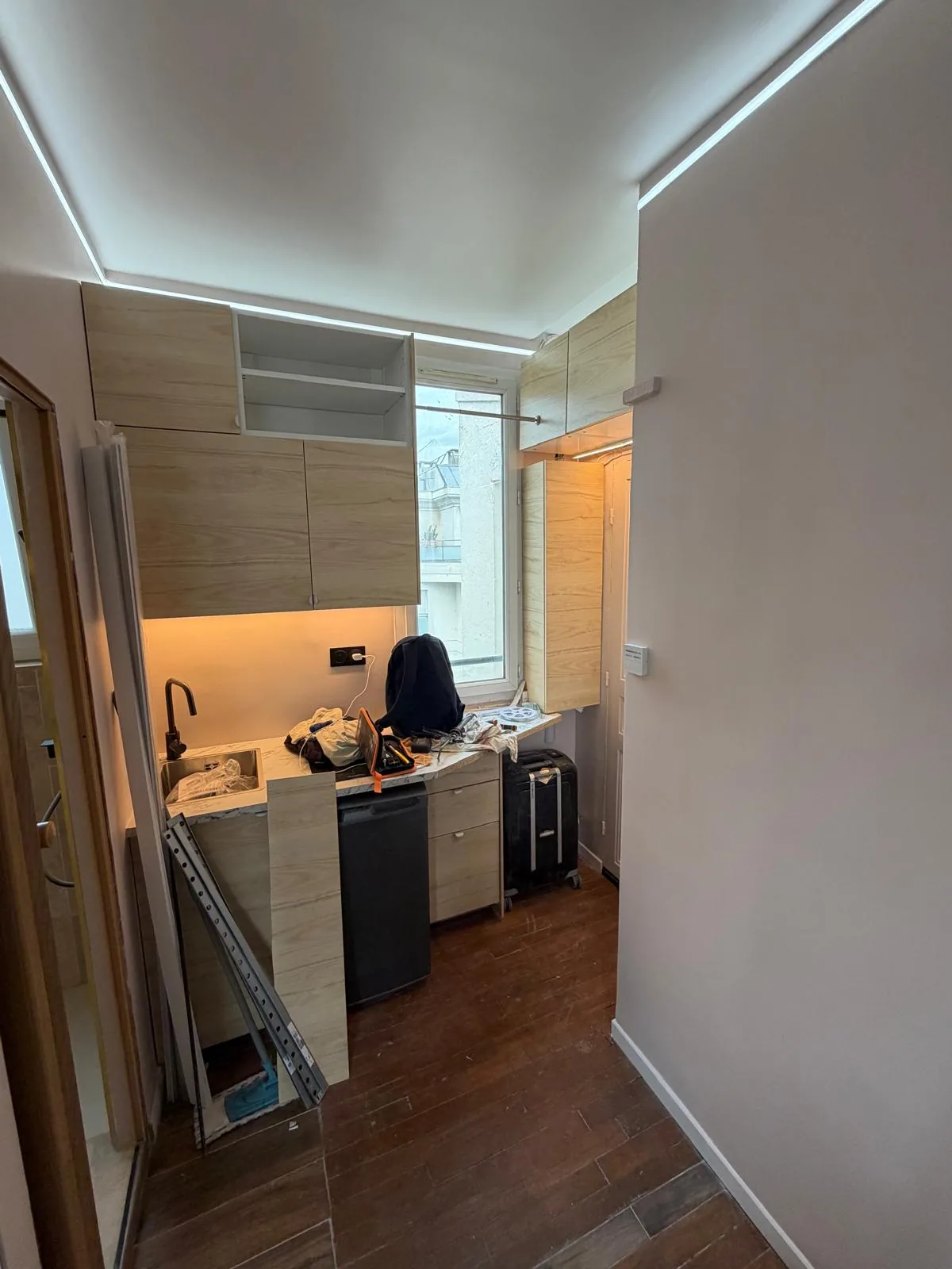 Cuisine du studio Montrouge en cours de pose : caissons hauts, plan de travail et évier sous film