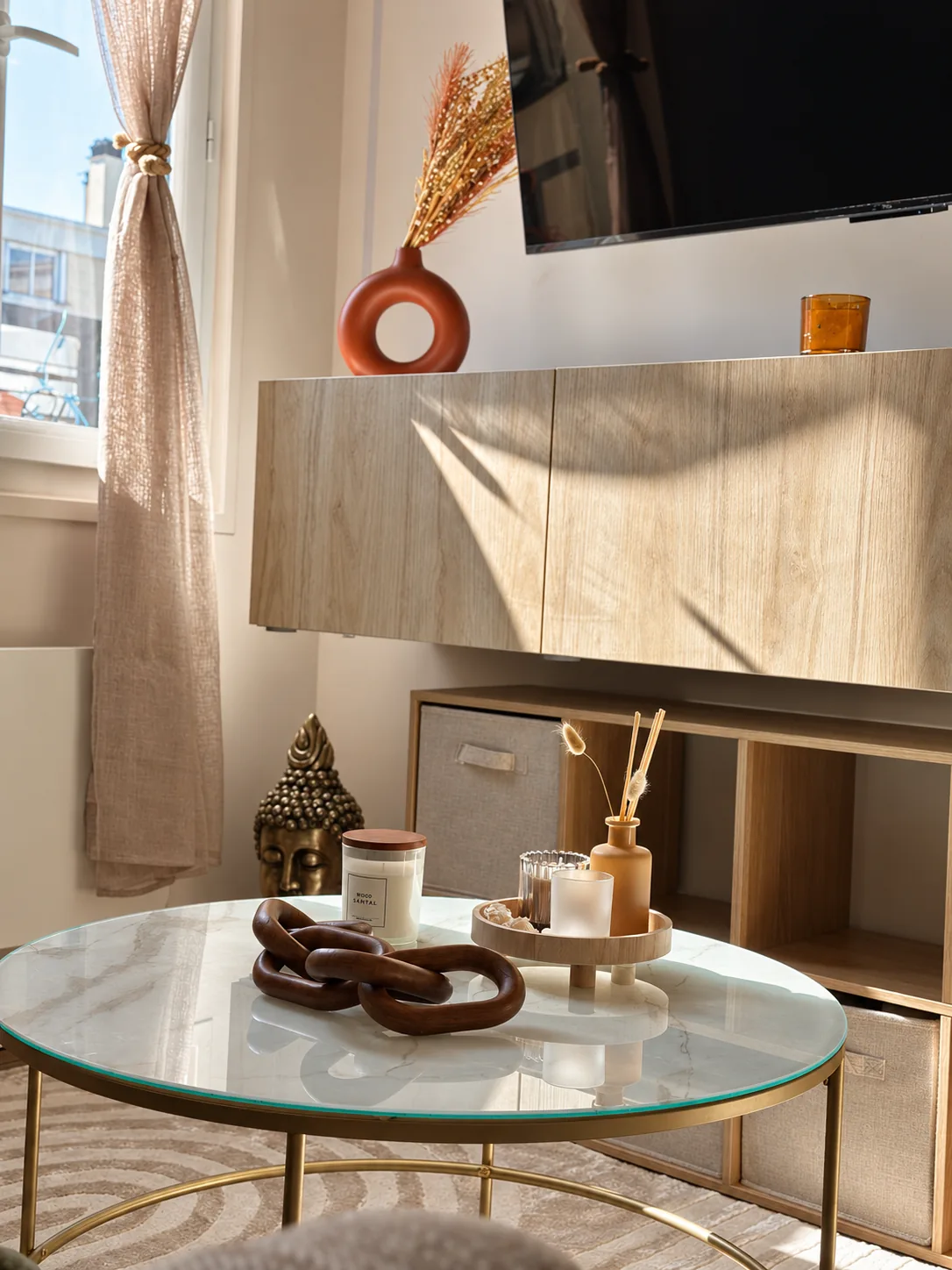 Détail : table basse en verre, objets en bois et lumière rasante