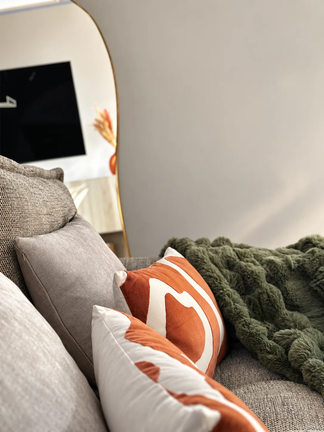 Détail : coussins terracotta et plaid vert sur le canapé